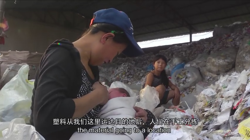 ‘China Plastics’ dokumentaletik ateratako irudian, protagonistetako bat den Ji-Jie neskatoak plastiko nahasien pila gainetik begiratzen die bere amari eta honi bularra hartzen dion ahizpa txikiari. 11 urterekin egunero ari dira lanean ama-alabak Txinako b